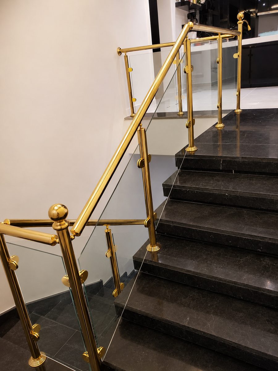 Polished brass posts and glass infill railing on a black marble staircase