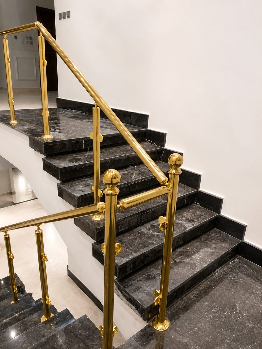 Polished brass handrail and ball-topped posts on black marble stairs