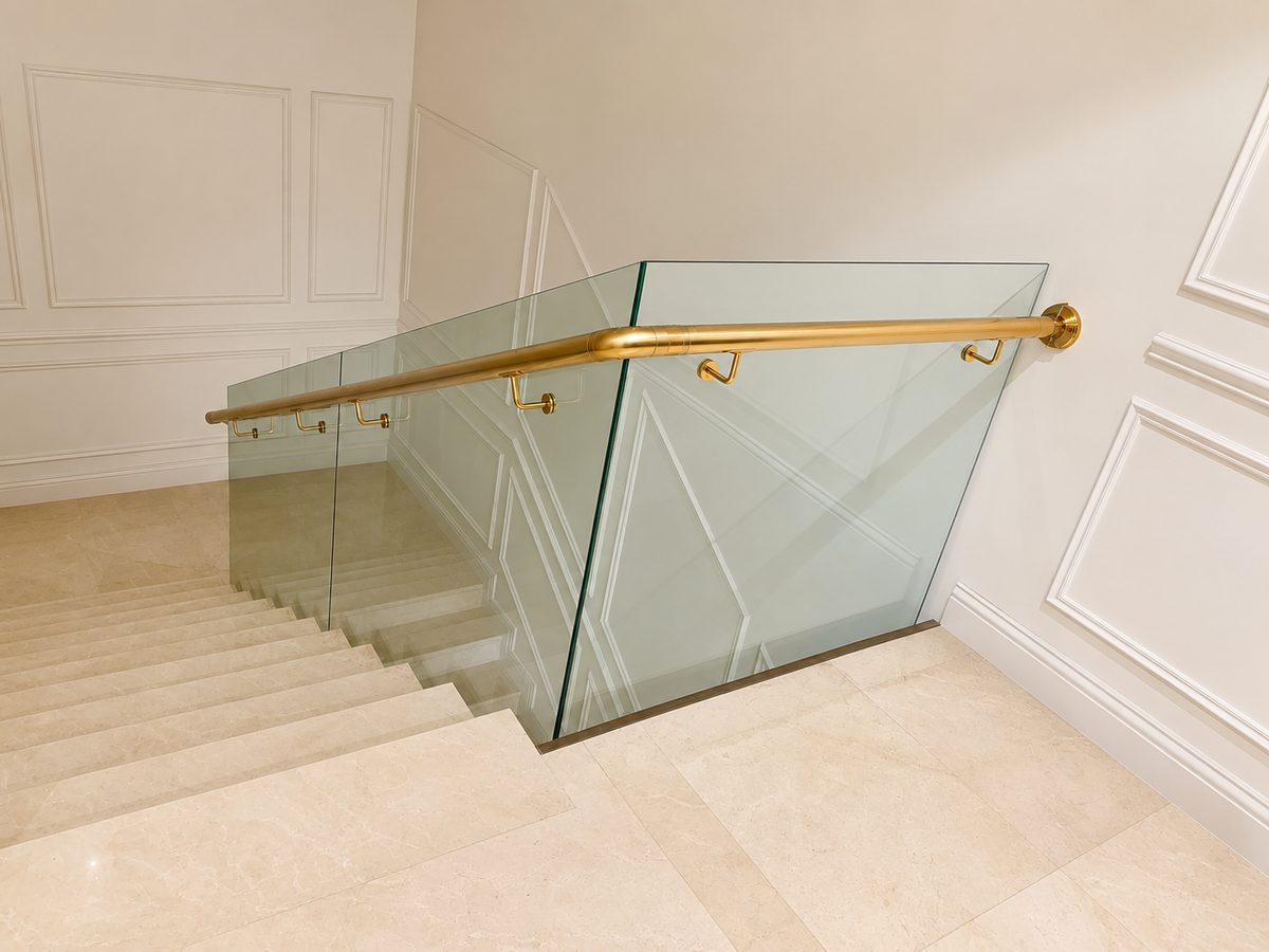 Frameless glass balustrade with a brass handrail on a marble staircase