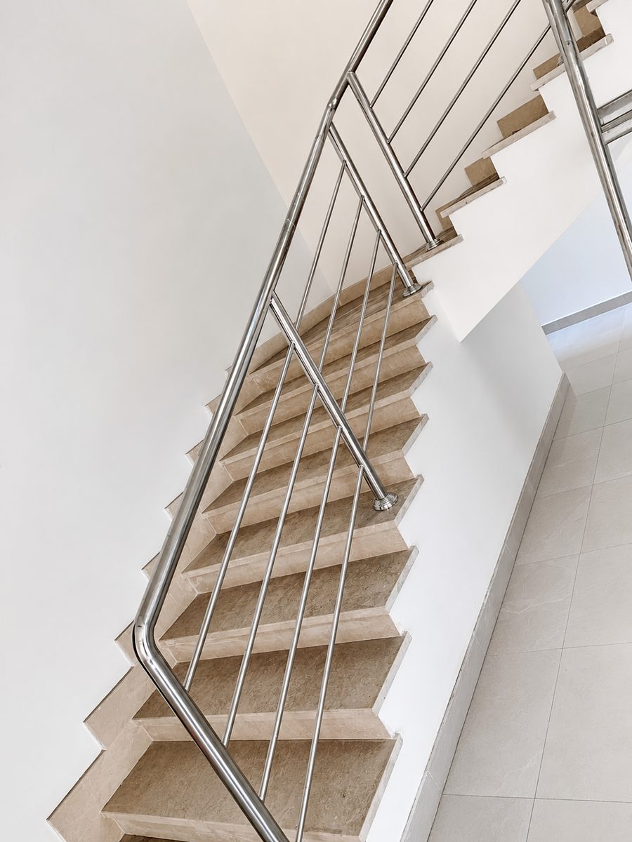 Stainless steel railing with brass ball detailing across two staircase flights